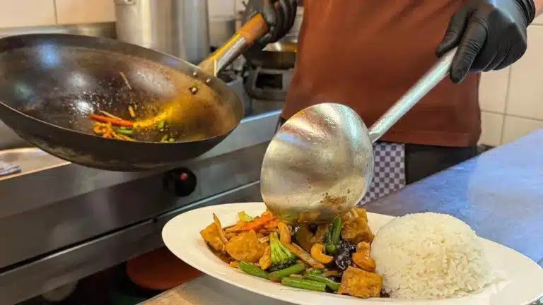 Phad Med Ma Muang vegan mit Tofu wird in der Küche von Pi-Nong aus dem Wok auf den Teller gegeben