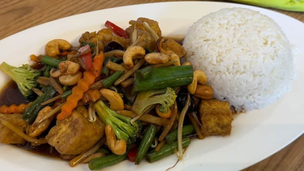 Cashewkerne zwischen Brokkoli, Bohnen und Tofu auf einem Teller im Pi-Nong